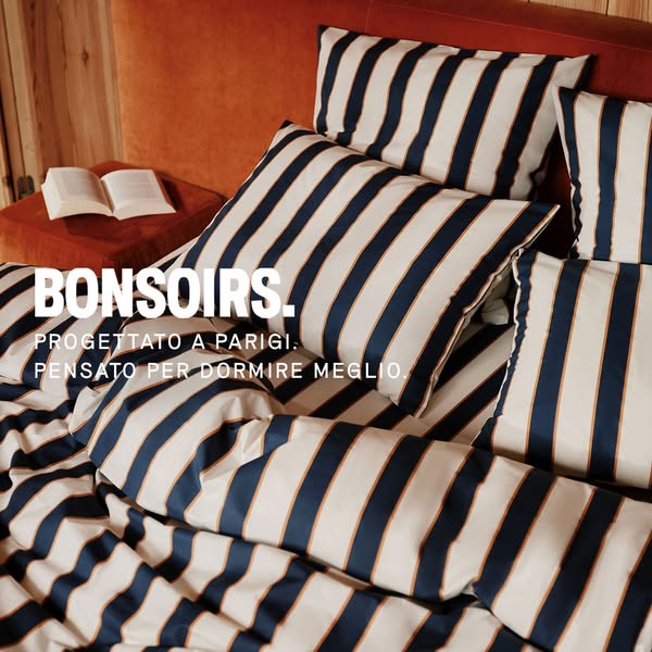This image ad is promoting BONSOIRS bedding. The ad features a close-up shot of a bed with striped sheets and pillows, a