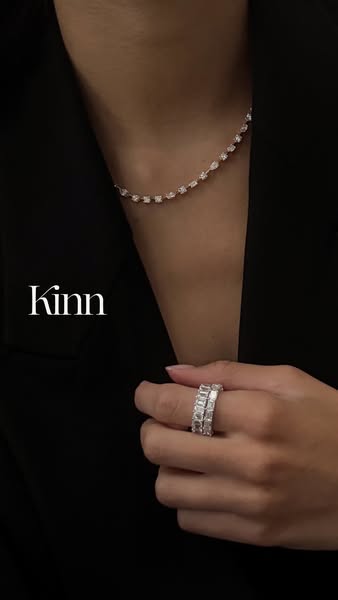 This ad showcases Kinn jewelry, specifically a diamond necklace and ring, on a person wearing a black blazer.