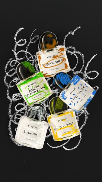 An artistic image ad for Byredo featuring five of their fragrances. The perfume bottles are arranged against a black bac