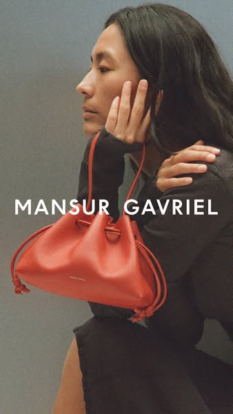 This ad showcases a red leather drawstring bucket bag from Mansur Gavriel. The ad features a person with long dark hair 