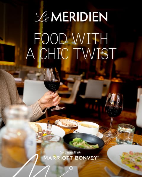 This ad for Le Meridien hotel features a close-up shot of a table full of food and wine in a restaurant setting. The cop