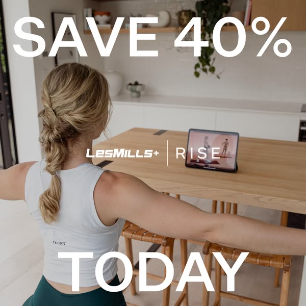 An image ad showcasing a woman exercising in her home. A tablet displaying the LES MILLS + RISE workout program sits on 