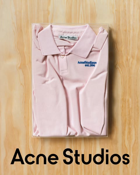 This image ad features a pink Acne Studios polo shirt in a clear container, placed on a wooden surface, with the brand n
