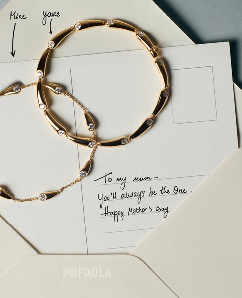 An ad for Popaola jewelry featuring a gold bracelet on top of a letter.