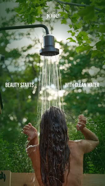 An image ad for Jolie's filtered showerhead shows a woman with long wet hair showering outdoors against a lush green