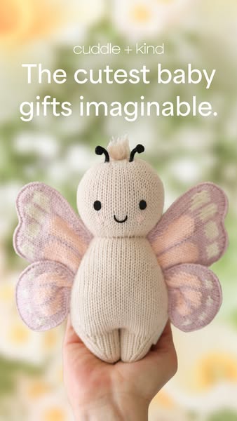 This ad features a close up of a Cuddle + Kind brand knitted butterfly doll being held in someone's hand. The text o