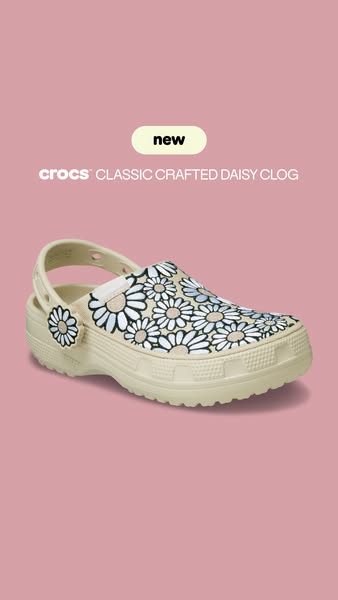This image ad showcases the new Crocs Classic Crafted Daisy Clog on a solid pink background. The design features a beige