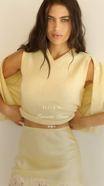 This image ad is promoting DÔEN knitwear. It features a model in a cream-colored knit sweater vest, cardigan, and skirt 