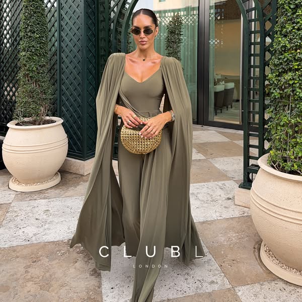 This image ad features a woman posing in an olive-colored jumpsuit with a cape draped over her shoulders, along with a s