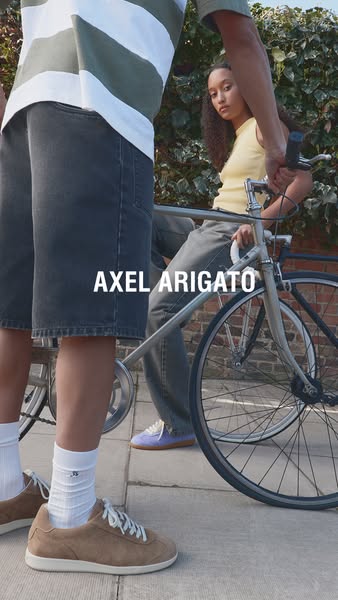 This image showcases Axel Arigato shoes in a lifestyle setting. Two people are shown with one riding a bicycle and both 