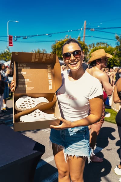 This ad features a woman holding an open shoe box with two shoes in it. The text on the side of the box points out the d