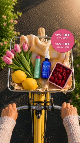 An image ad featuring Boom! By Cindy Joseph products being transported in a bicycle basket with tulips, lemons, and rasp