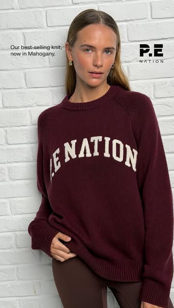 This image ad features a woman modeling the P.E Nation best-selling knit sweater in the new mahogany color.