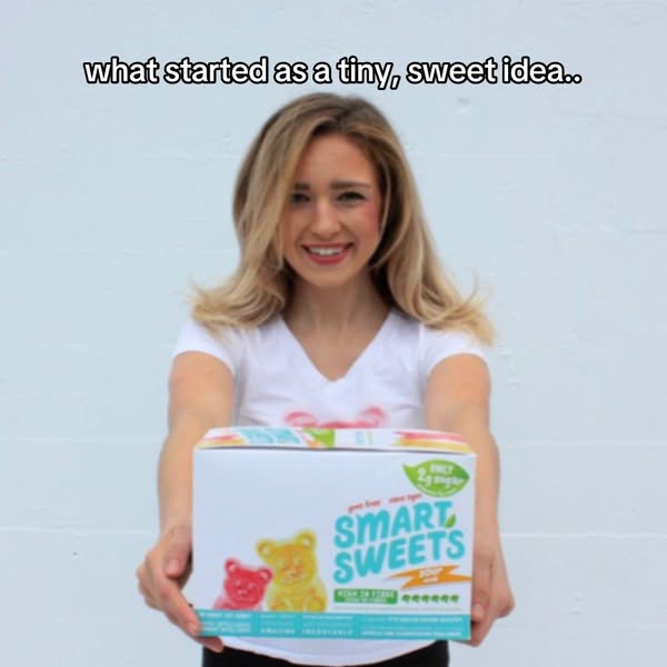 The ad features a woman holding up a box of Smart Sweets candy, emphasizing its low sugar content and how it originated.