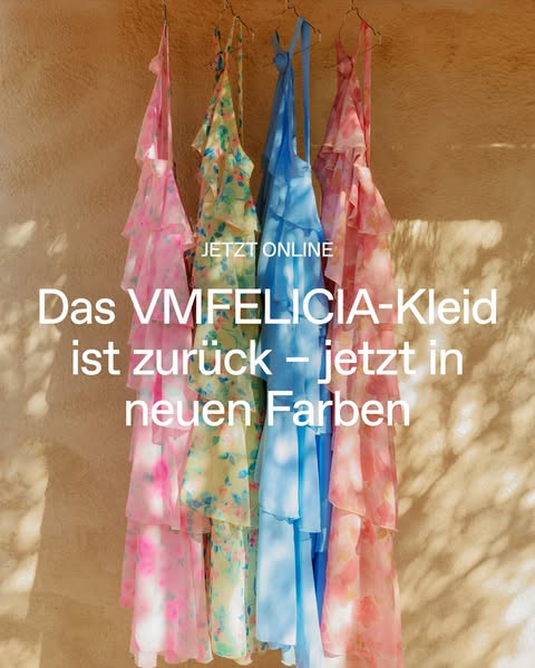 This image showcases a selection of tiered dresses against a sunlit wall, emphasizing the new colors available.