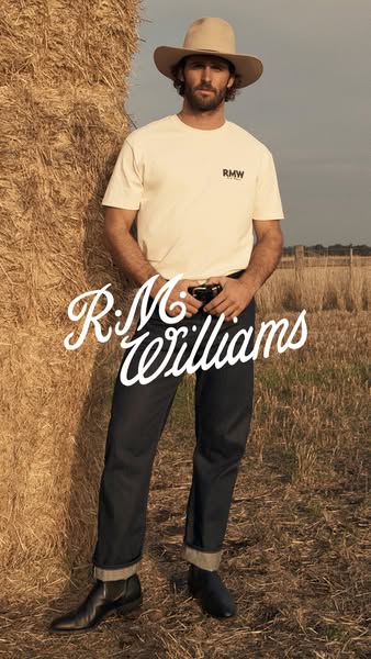 This image ad features a man wearing clothing and boots from R.M. Williams. He's leaning against a bail of hay in a 