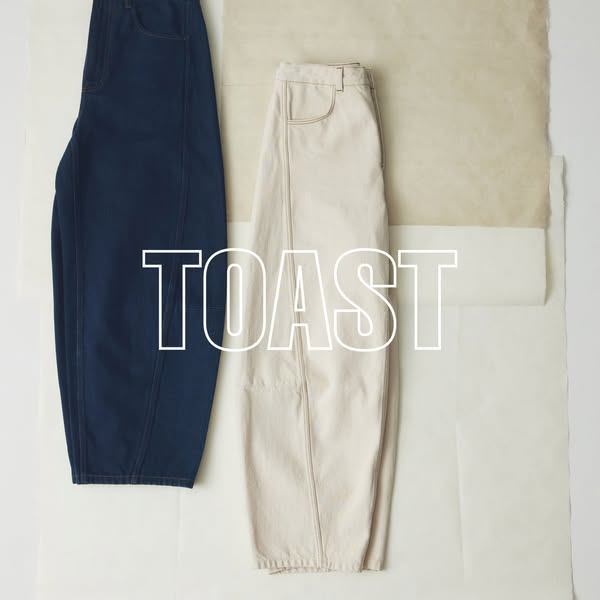 This ad features two pairs of TOAST balloon leg pants. One is indigo denim and the other is beige cotton. They are artfu