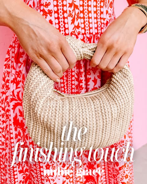 This image ad for Tribe & Grace features a woman holding the brand's handbag in front of a pink wall and red flo