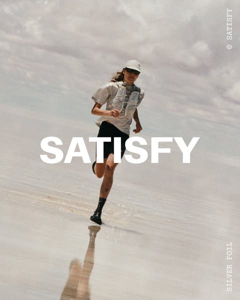 A lone runner sprints across a white flat expanse of land, wearing a metallic silver running vest. The ad highlights the