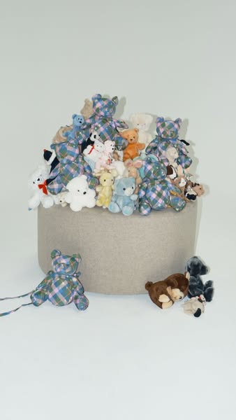 This ad features a collection of teddy bears with a blue and pink plaid pattern. The bears are arranged on a round, gray