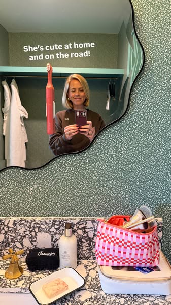 Image ad featuring a woman in a bathroom taking a selfie in the mirror, which reflects a bathroom vanity area with a too