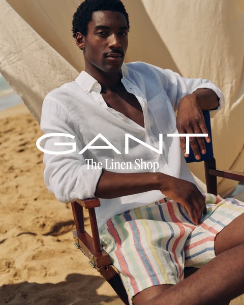 The image features a man in a linen shirt and shorts, promoting GANT's linen collection, positioned in a beach setti