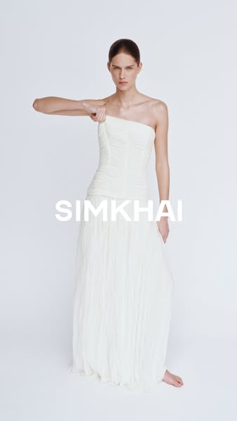 This image ad features a single model wearing a strapless white gown from SIMKHAI against a solid white background. The
