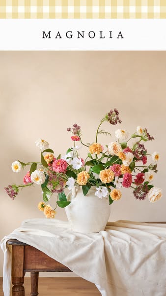 This is a still image ad promoting Magnolia. The focal point is a cream-colored vase filled with an abundant mix of flow