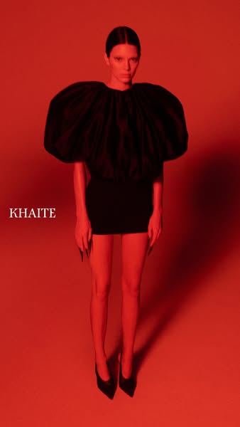 A striking fashion ad presents a model in a unique black dress against a monochromatic red backdrop, emphasizing the gar