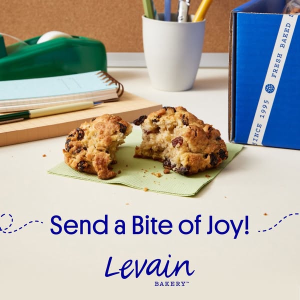 This ad shows a partially eaten Levain Bakery cookie on a desk or table with office supplies as a way to promote sending