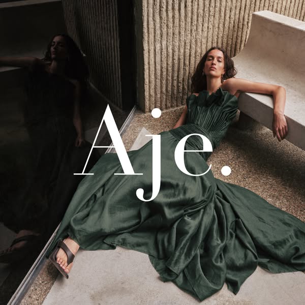 This image ad showcases a woman in an elegant green dress made by Aje.