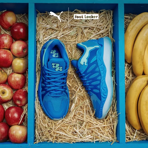 The image ad showcases blue PUMA sneakers in a box filled with straw, alongside apples and bananas, promoting their avai