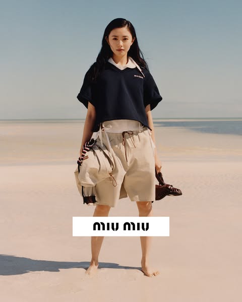 The ad features a young woman standing on a beach, wearing Miu Miu clothing. The Miu Miu brand name is in a rectangle in
