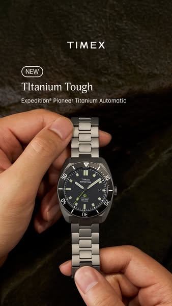 An image showcasing a Timex watch from the Expedition Pioneer Titanium Automatic line. The watch is held by a pair of ha