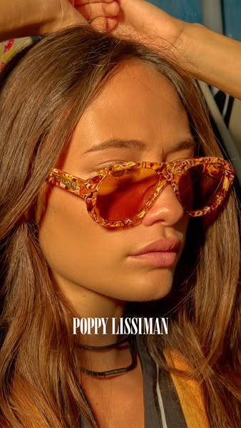 This image ad showcases aviator-style sunglasses from Poppy Lissiman featuring a chunky frame and amber-tinted lenses.