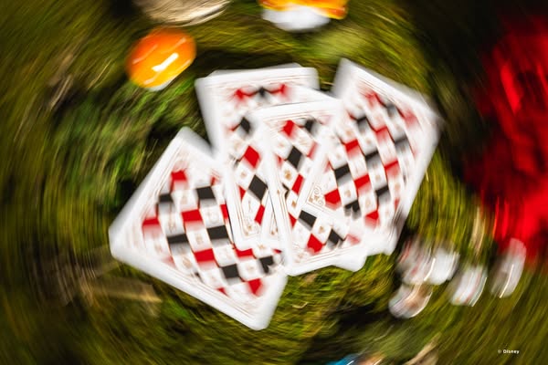 This ad features playing cards on green moss with a blurry swirling effect, likely referencing the Queen of Hearts from 