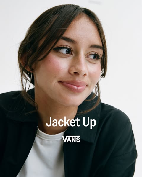 A promotional image for Vans featuring a dark-colored jacket worn by a woman.