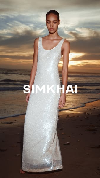 This ad features a woman wearing a floor-length, sleeveless gown against a beach sunset backdrop and promotes the brand