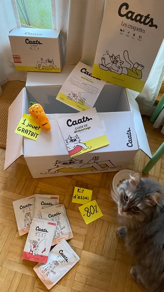 This ad features Caats cat food and a promotional offer. It includes an unboxing aesthetic with an open box and cat near