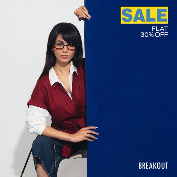 This is a promotional ad by Breakout featuring a woman in glasses, a maroon shirt, and distressed jeans, sitting in fron