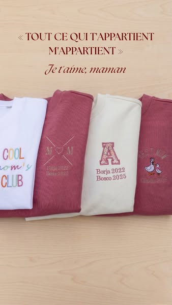 This image ad displays four folded sweatshirts, each with custom embroidery, on top of a light wooden surface. The ad pr
