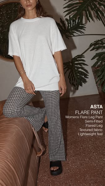 An ad showcasing a woman modeling a pair of Asta brand women's flare leg pants. The ad highlights the semi-fitted an