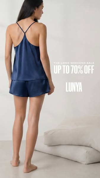 This ad for Lunya features a woman wearing a navy blue pajama set. The ad highlights a long weekend sale, offering up to