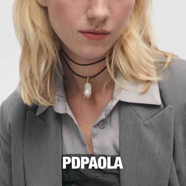 This ad features a close-up shot of a woman wearing a PDPaola baroque pearl choker. The overall aesthetic is clean and m