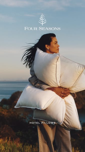 This image ad for Four Seasons Hotel Pillows features a woman outdoors, holding two pillows. The ad focuses on the comfo