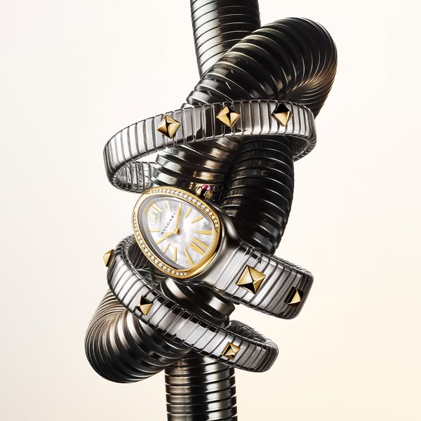 This ad features a Bvlgari Serpenti watch wrapped around a black, ridged metal tube. The composition and lighting highli