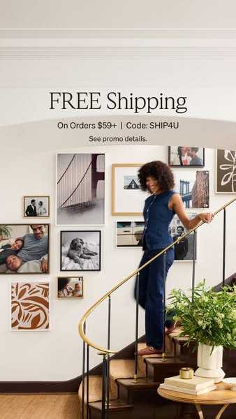 This image ad showcases a collection of framed photos displayed on a wall with a woman walking up a staircase in front o