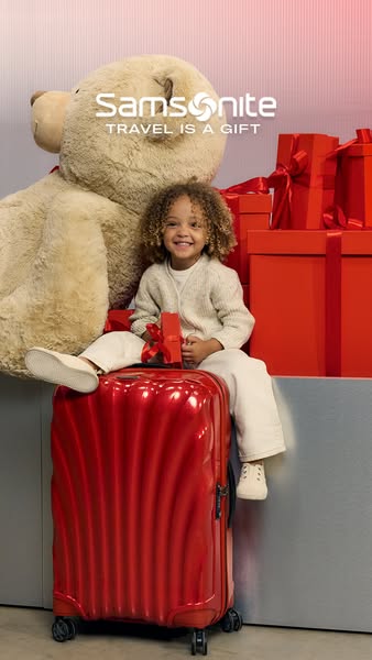 This ad features a young girl sitting on a red Samsonite suitcase, surrounded by a teddy bear and gift boxes, emphasizin