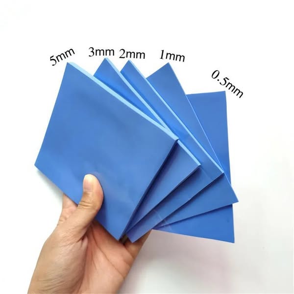 An image showcasing different thickness sizes of thermal pads. The pads are being held by a hand and the thicknesses are