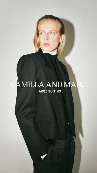 This image ad for Camilla and Marc showcases a model wearing a black blazer and coordinating pants, accessorized with a 